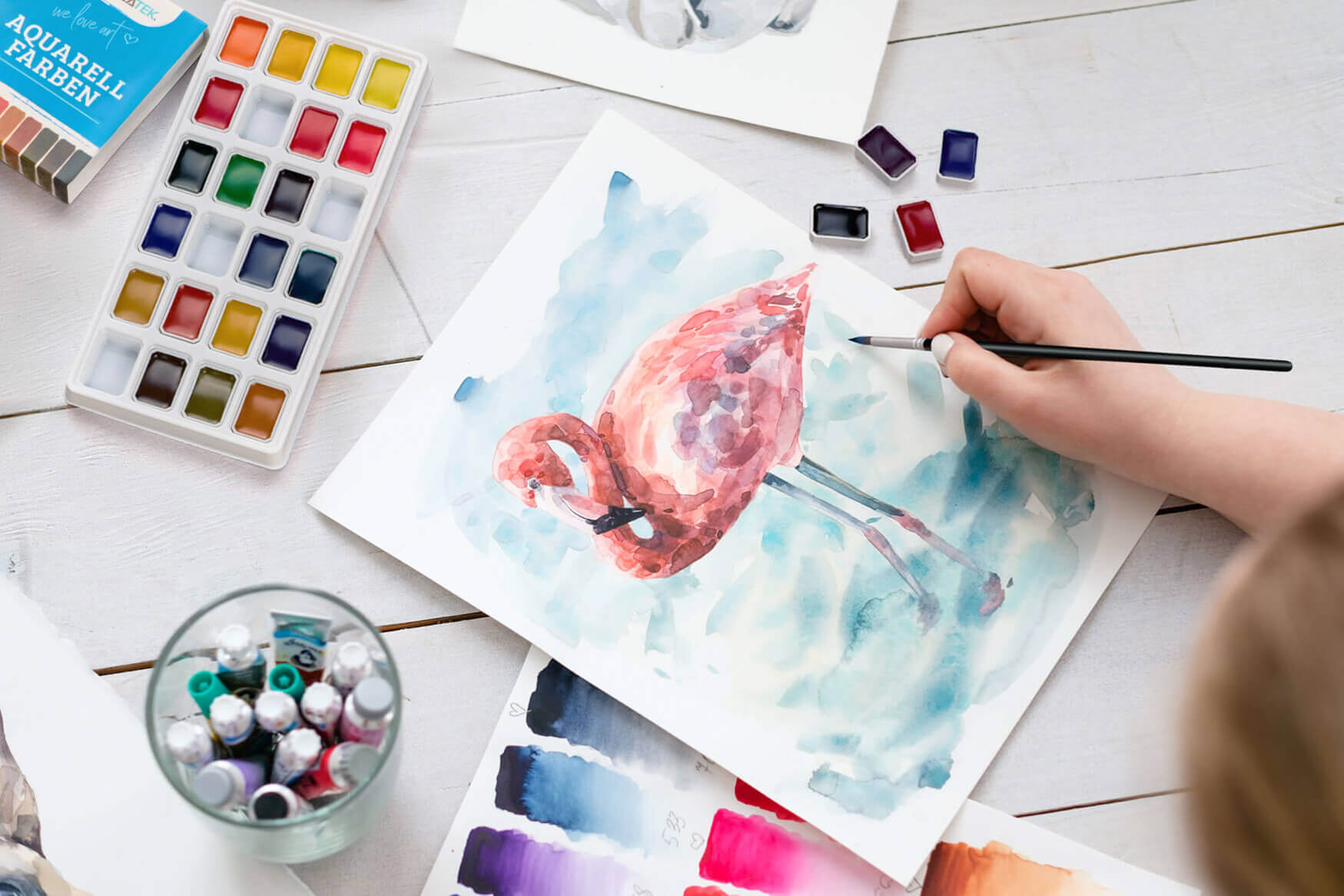 Ein faszinierendes Lifestyle-Foto, das ein Gemälde, Aquarellfarben und Pinsel zeigt. Unsere Produktfotografie fängt die künstlerische Inspiration und den kreativen Prozess der Malerei ein und lädt dazu ein, die Welt der Farben und Formen zu erkunden.