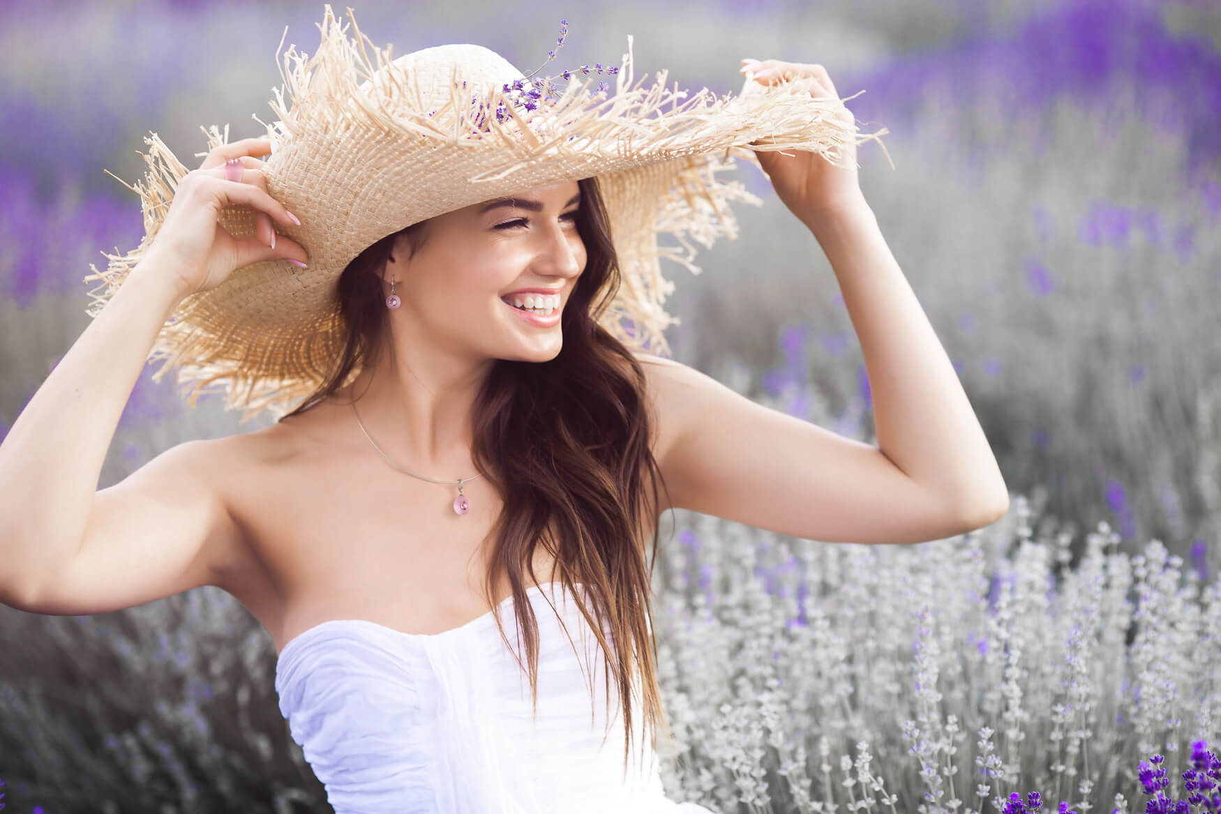 Ästhetische Fotografie einer Frau im Lavendelfeld mit einem großen Strohhut, die eine schöne rosafarbene Kette präsentiert. Perfekt für die Darstellung von Schmuck und Lifestyle-Produkten. Hochwertige Aufnahme für Ihre Markenfotografie und Produktpräsentation.