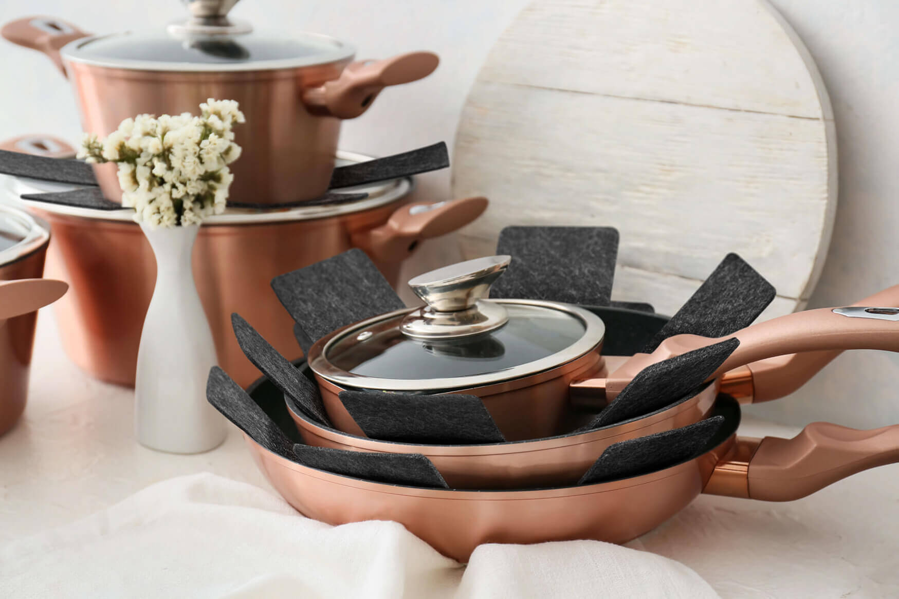 Ein beeindruckendes Werbefoto eines Topfsets, präsentiert mit Filzuntersetzern zur Trennung der Töpfe. Unsere Produktfotografie zeigt die Eleganz und Organisation dieses Sets, das nicht nur stilvoll aussieht, sondern auch Ihre kuechenoberflächen schützt und die Handhabung erleichtert.