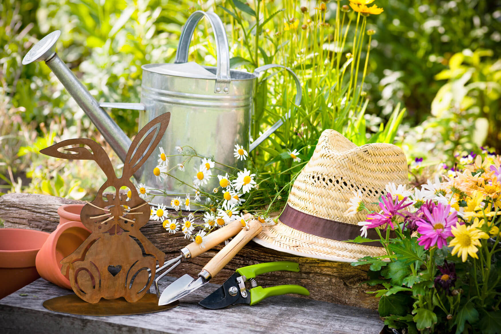 Ein malerisches Lifestyle-Foto präsentiert einen rostigen Deko-Hasen, der sich mitten im Blumenbeet befindet. Unsere Produktfotografie fängt die natürliche Schönheit und die verspielte Note dieses dekorativen Elements ein, das Ihren Außenbereich mit einem Hauch von Nostalgie und Charme bereichert.