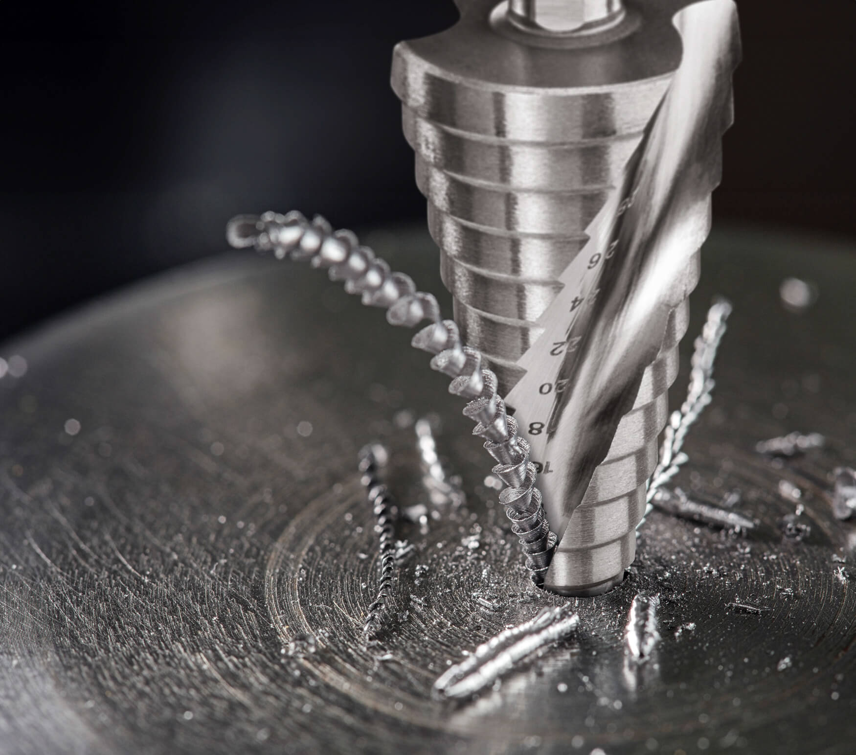 Entdecken Sie die Präzision und Kraft: Unser fesselndes Composing zeigt einen Edelstahl-Stufenbohrer in Aktion, während er sauber bohrt und Späne ausstößt.