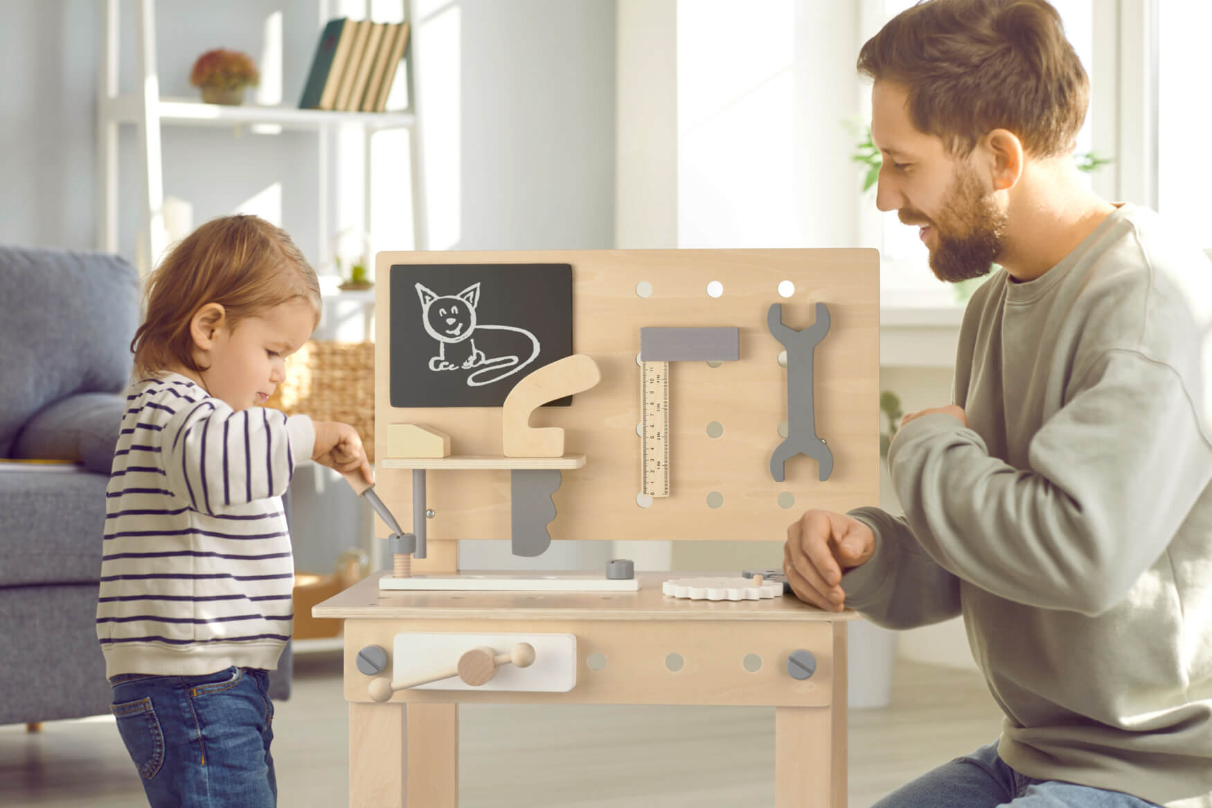 Ein Vater spielt mit seinem Kind an einer Spielzeugwerkbank, wobei sie gemeinsam handwerkliche Fähigkeiten erkunden und die Bindung zwischen ihnen stärken. Diese herzerwärmende Szene zeigt die Freude am Spielen und Lernen im familiären Umfeld.
